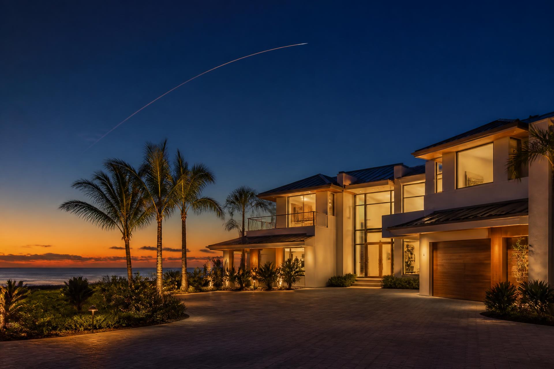 Modern Florida coastal home at golden hour with a rocket contrail overhead